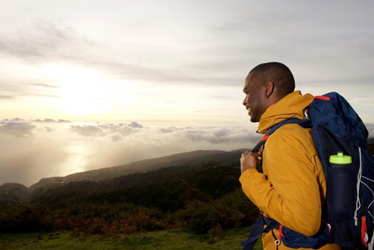 happy african american hiker looking at view from mountain