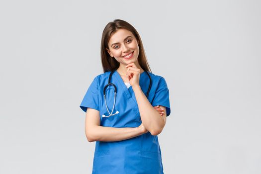 Medical workers, healthcare, covid-19 and vaccination concept. Upbeat smiling pretty nurse, doctor in blue scrubs, working clinic, looking with enthusiastic gaze camera, listening to coworker