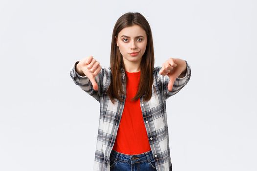Lifestyle, different emotions, leisure activities concept. Skeptical and disappointed young woman smirk unsatisfied and showing thumbs-down in dislike, disapprova and judging bad product