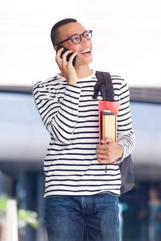 cheerful young man laughing while talking on mobile phone at college campus