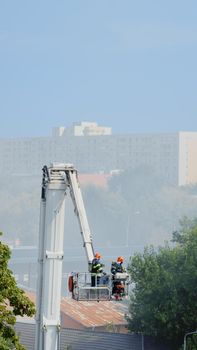 View of firefighters using platform truck to extinguish fire