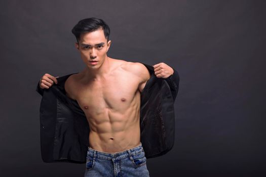 Strong, fit and handsome asian young  man over black background
