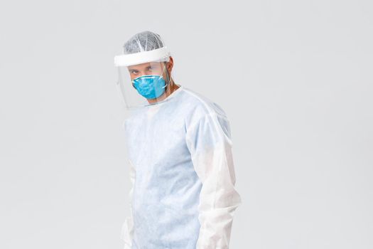 Covid-19 pandemic, virus outbreak, healthcare workers concept. Serious determined doctor in personal protective equipment, look confident camera, tackle coronavirus outbreak, treat patients
