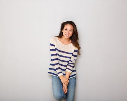 beautiful young asian woman smiling with striped sweater against gray background