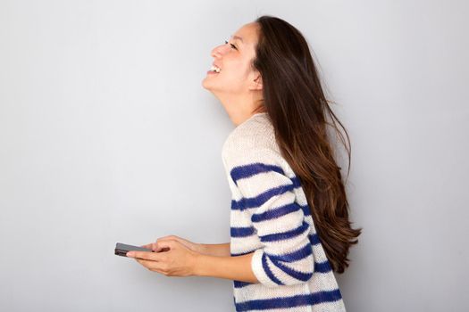 pretty asian woman smiling with smart phone against gray background