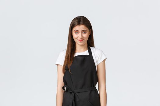 Grocery store employees, small business and coffee shops concept. Skeptical and awkward female barista smirk and looking uncomfortable as telling unpleasant news, white background