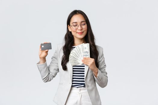 Business, finance and employment, entrepreneur and money concept. Successful pleased businesswoman earn cash, smiling with satisfaction, showing dollars and credit card