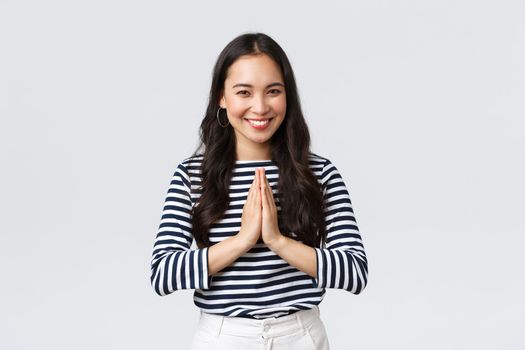 Lifestyle, people emotions and casual concept. Cute asian girl in casual outfit smiling as saying namaste, holding hands in pray, pleading or greeting guests with polite bow