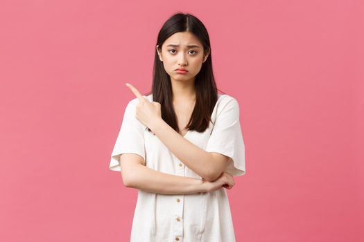 Beauty, people emotions and summer leisure concept. Upset gloomy girl in white dress, sulking and frowning as pointing upper left corner at bad news, disappointing advertisement banner