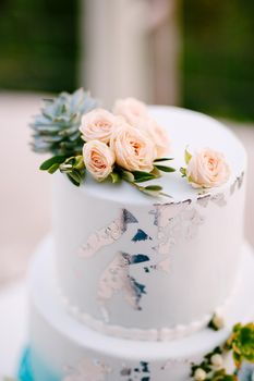 Top tier of a wedding cake decorated with roses and succulents