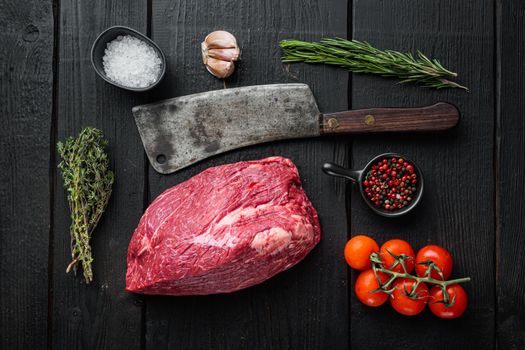 Beef meat cut raw with old butcher cleaver knife, on black wooden table background, top view flat lay