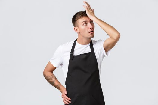 Employees, grocery stores and coffee shop concept. Annoyed and bothered barista, cafe manager or waiter, punch forehead, facepalm and eye roll irritated, standing white background