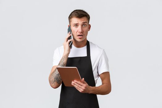 Retail stores, small business, cafe and restaurants takeaway concept. Confused and worried, unsure salesman receive complain from customer over phone, look nervous camera, holding digital tablet