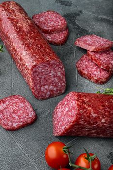 Dry salami sausage with fresh rosemary and spices, on gray stone table background