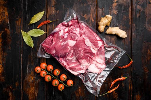 Fresh raw mutton shoulder meat, with ingredients and herbs, on old dark wooden table background, top view flat lay