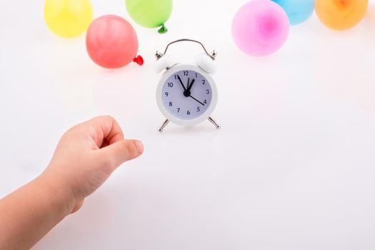 Hand and alarm clock  with balloons around 