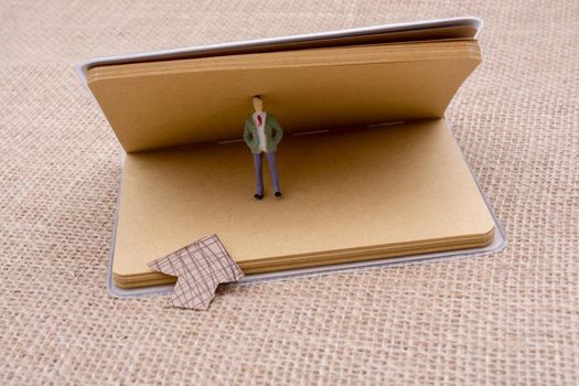 Figurine and an paper arrow in a notebook