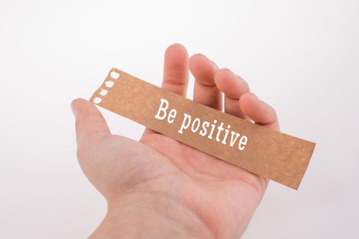 Be positive quote lettering on torn notepaper in hand