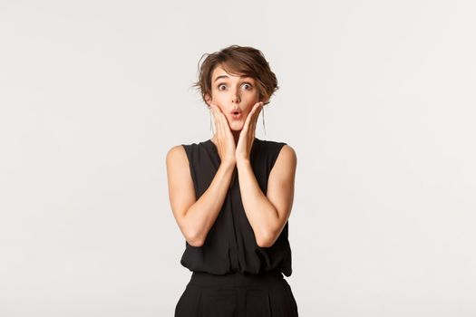 Image of surprised fashionable woman looking with amazement and excitement, standing white background