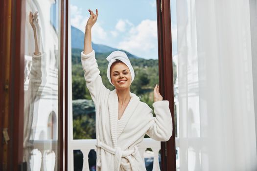 cheerful Woman in a White robe stands in the doorway on the balcony