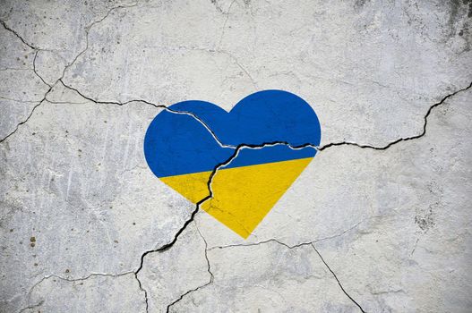 The symbol of the national flag of Ukraine in the form of a heart on a cracked concrete wall.