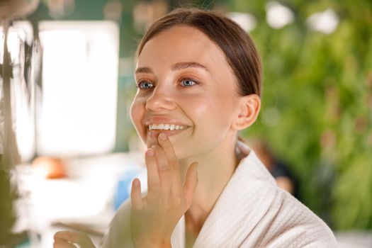 Closeup portrait of natural young woman with beautiful smile and perfect skin having beauty routine in the bathroom