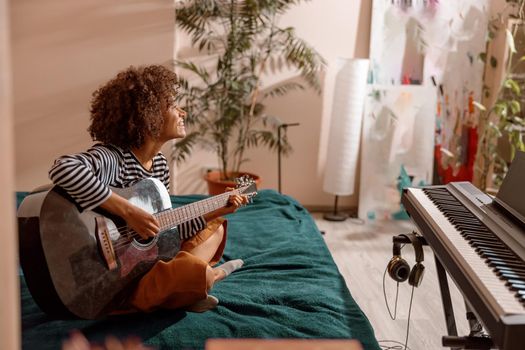 Cheerful female guitarist playing guitar at home