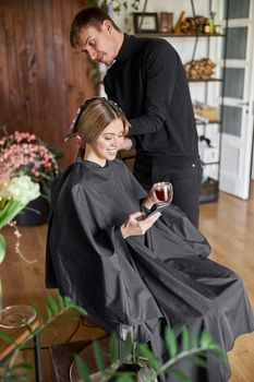 Confident male stylist is dyeing hair of blond caucasian female client