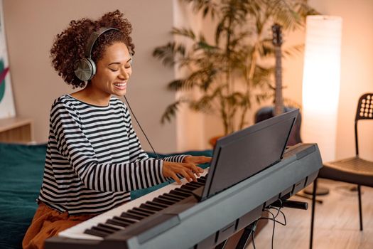 Cheerful female musician playing synthesizer at home