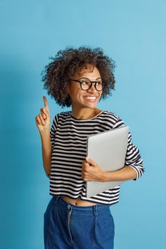 Joyful young woman with laptop pointing finger up
