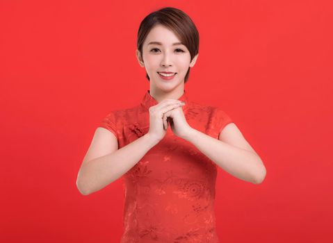 Chinese woman in a cheongsam dress with a congratulations gesture