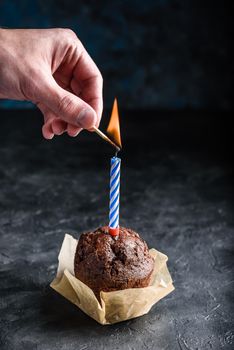 Hand lighting candle on birthday muffin