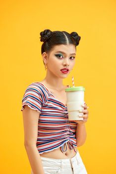 Portrait of fascinating girl wearing striped t-shirt drinking chocolate isolated on yellow background