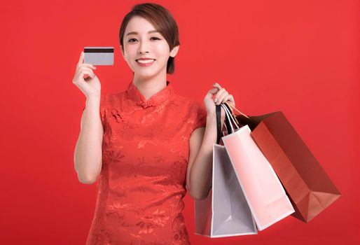 Happy chinese new year. Happy young Woman showing credit card and holding the shopping bags