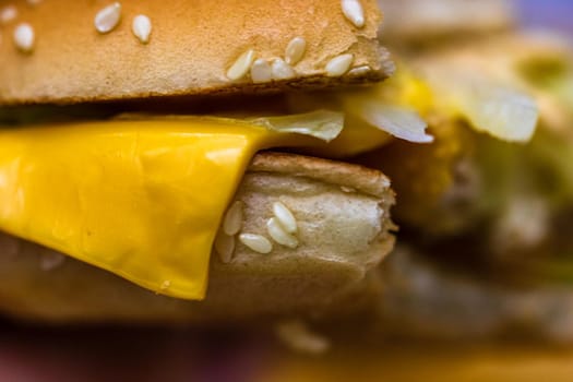 Close up detail of a bitten cheeseburger. Food, junk food and fast food concept