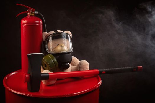 the mascot of the fire brigade is a teddy bear in a gas mask with a fire extinguisher and a red axe in smoke on a dark background