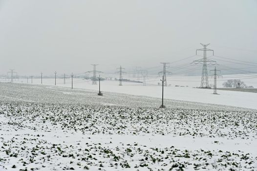 High voltage pylons in winter landscape with snow. Expensive heating in winter and rising electricity prices in Europe.