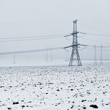 High voltage pylons in winter landscape with snow. Expensive heating in winter and rising electricity prices in Europe.
