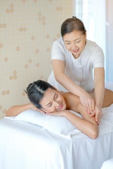 Portrait of Asian beautiful woman lie on bed and get the spa massage in the room with day light.