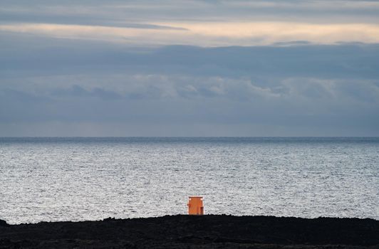 Orange tiny lighthouse facing the huge ocean