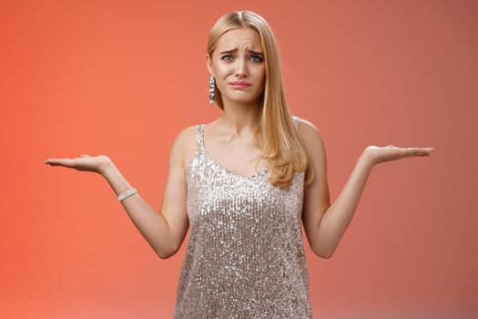 Nervous unsure doubtful cute blond woman struggle make decision shrugging pointing sideways frowning upset standing insecure feel pressure cannot decide choice make, frustrated red background
