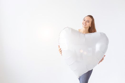 Beautiful young woman with heart shape air balloon on white background with copy space. Woman on Valentine's Day. Symbol of love