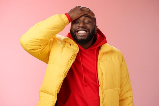 Charming cute black bearded 25s guy forget something stupid silly smiling friendly punch forehead grinning feel awkward say sorry standing pink background joyfully relaxed