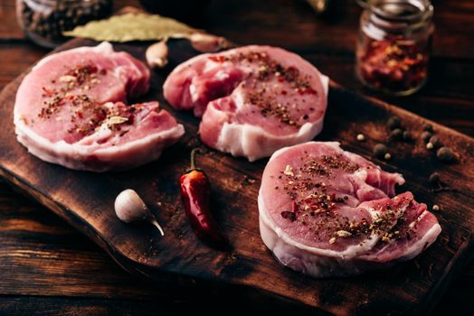 Pork loin steaks with ground spices on cutting board