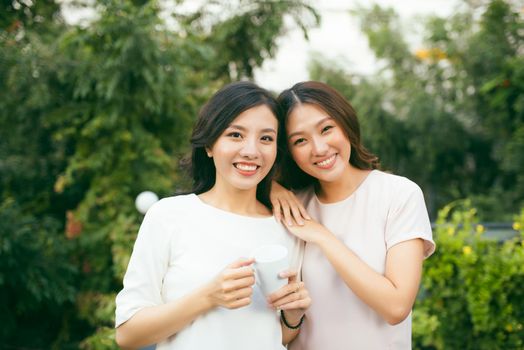 Two beautiful young well-dressed women chatting outdoors over coffee