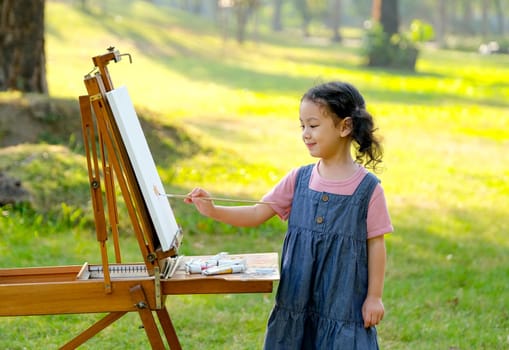 Lovely little girl show happy smile and enjoy with painting in the garden with morning light.