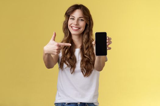 Upbeat confident good-looking female showing photo smartphone display hold mobile phone extended arm camera pointing index finger cellphone screen smiling delighted promote app internet application