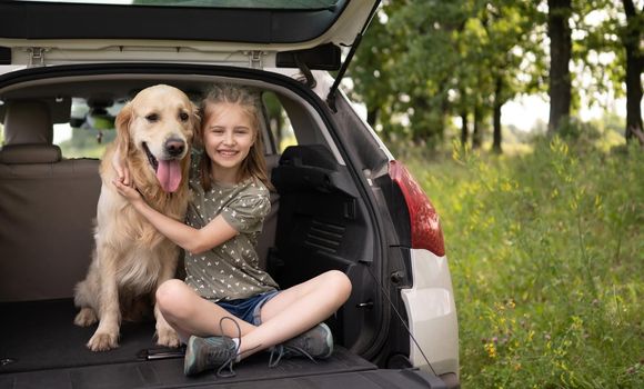 Preteen girl with golden retriever dog in the car