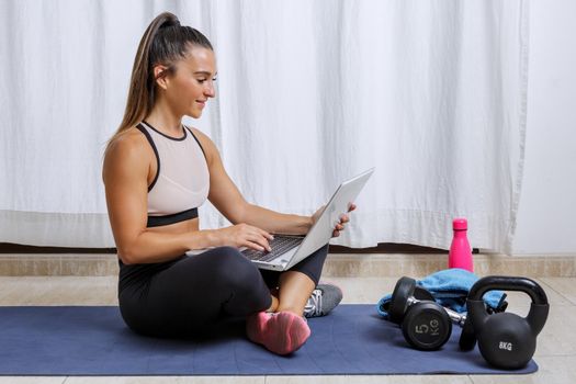 Positive woman using laptop during workout at home