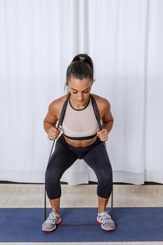 Fit woman squatting with resistance band